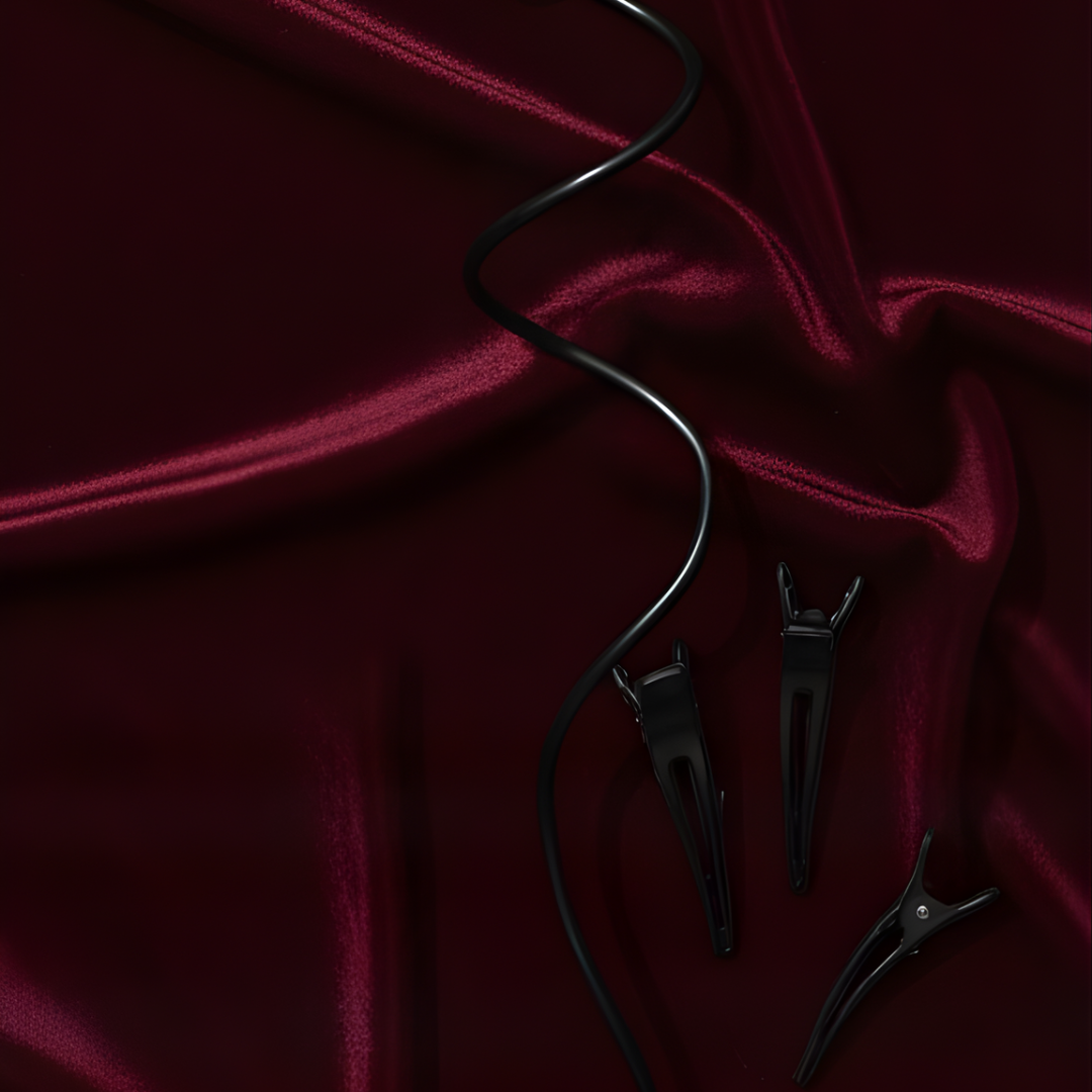 Black hair styling tools on a maroon fabric background